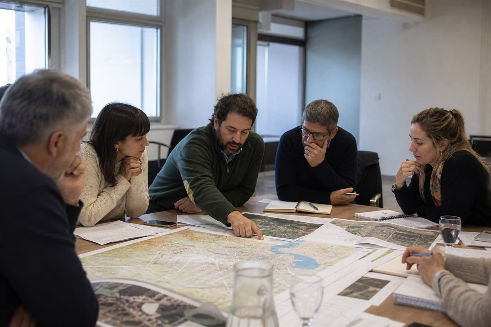 Equipos técnicos analizan mapas y proyectos en una mesa de trabajo